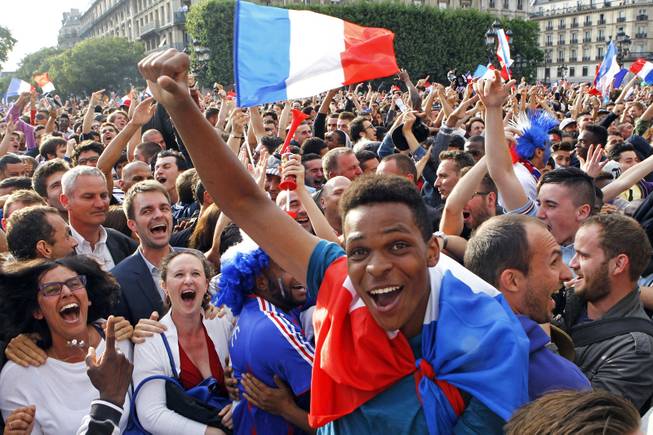 French soccer fans celebrate after France scored the first goal, as they watch the World Cup soccer match between France and Nigeria being shown live on a giant screen, in front of Paris City Hall, Monday June 30, 2014. France won the match 2-0, played at the Estadio Nacional stadium in Brasilia, Brazil.