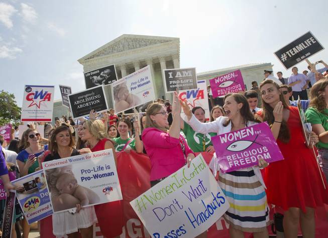 Demonstrator react to hearing the Supreme Court's decision on the Hobby Lobby case outside the Supreme Court in Washington, Monday, June 30, 2014. The Supreme Court says corporations can hold religious objections that allow them to opt out of the new health law requirement that they cover contraceptives for women.