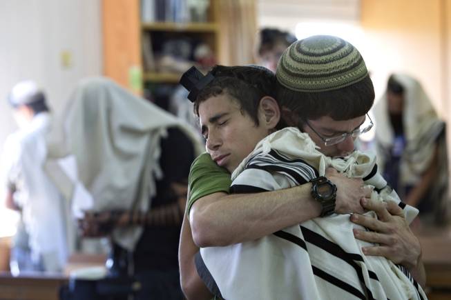 In this Sunday, June 15, 2014, photo, Israeli Jewish religious students hug prior to a prayer at the synagogue where two of the missing Israeli teens studied, in the Jewish settlement of Kfar Etzion.