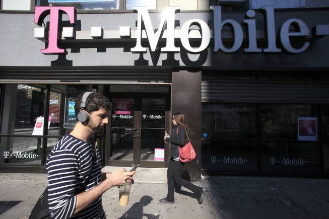 This Sept. 12, 2012, file photo shows a man using a cellphone as he passes a T-Mobile store in New York.