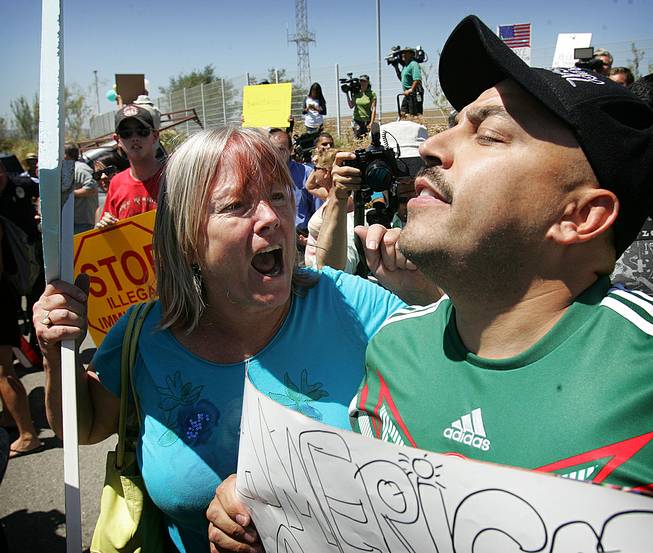 An unidentified protester, left, argues with U.S. citizen Lupillo Rivera, brother of Mexican-American singer Jenni Rivera, as three buses carrying 140 immigrants attempt to enter the Murrieta U.S. Border Patrol station for processing Tuesday, July 1, 2014.