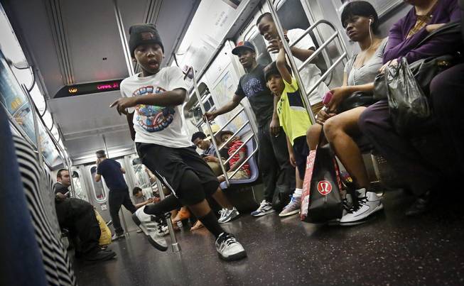 In this June 17, 2014 photo, Marc Mack, 8, a member with the dance troupe W.A.F.F.L.E., performs on a subway, in New York. Police Commissioner William Bratton's department "broken window" crackdown has targeted illegal motorcycles, graffiti and the subway acrobats. 