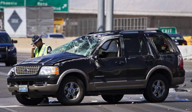 A Las Vegas Metro Police Officer pauses while working the scene of a fatal car crash on the I-15 just north of the I-95 interchange on Wednesday, July 2, 2014.