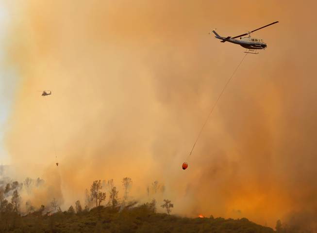 Private-hire helicopters make water drops on the Butts Fire above Snell Valley as the afternoon winds kicked up Wednesday, July 2, 2014, near Middletown, Calif.
