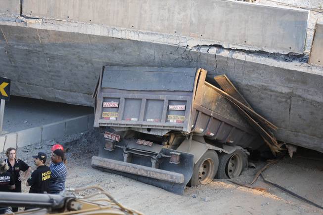 A truck is trapped underneath a collapsed bridge in Belo Horizonte, Brazil, Thursday, July 3, 2014. The overpass under construction collapsed Thursday in the Brazilian World Cup host city.