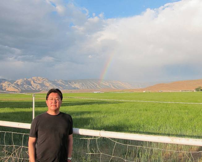 Simon Wen Shao is co-owner of the Escalante Ranch, a 22,000-acre ranch in northeast Utah that grows alfalfa for export back to diary industries in China, where Shao was born. Shao, who bought the ranch with a partner in 2011, stands before one of his alfalfa fields, with Dinosaur National Monument and a rainbow in the background, outside Jensen, Utah on June 11, 2014.