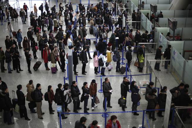 In this Jan. 20, 2012, file photo, passengers queue up for a security check at Pudong International Airport in Shanghai, China. The Transportation Security Administration is requiring passengers at some overseas airports that offer U.S.-bound flights to power on their electronic devices, the agency said Sunday, July 6, 2014. It says devices that won’t power up won’t be allowed on planes, and those travelers may have to undergo additional screening.