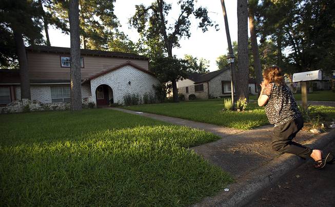 Patti Beller prays Thursday, July 10, 2014, in Spring, Texas, outside the home that was the scene of a multiple shooting the night before. The Harris County Sheriff's Office says Ronald Lee Haskell was booked Thursday on a capital murder/multiple murders charge and held without bond.