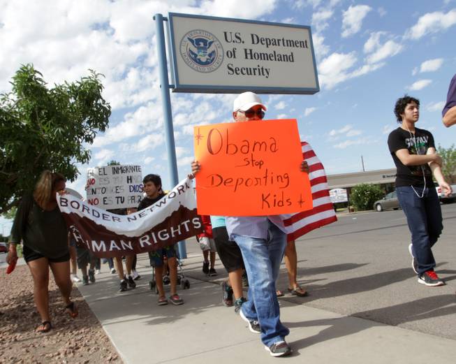 Marchers held signs as they made their way to Department of Homeland Security offices, protesting immigration policies Thursday, July 10, 2014, in El Paso, Texas.
