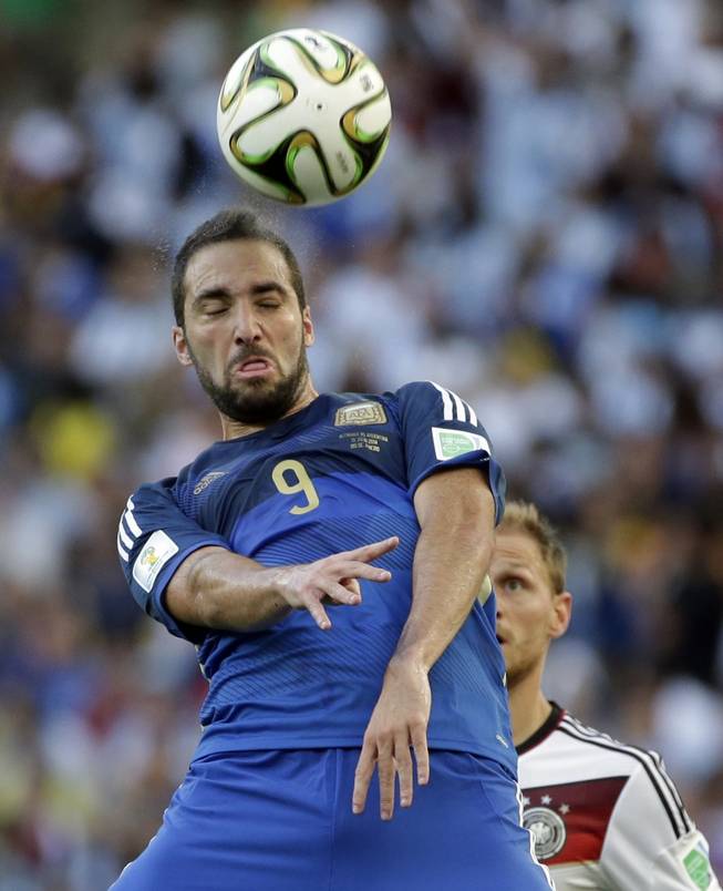 Argentina's Gonzalo Higuain heads the ball in front of Germany's Benedikt Hoewedes during the World Cup final soccer match between Germany and Argentina at the Maracana Stadium in Rio de Janeiro, Brazil, Sunday, July 13, 2014.