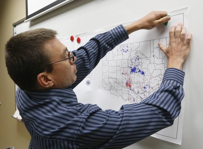 In this June 26, 2014 file photo, Austin Holland, research seismologist at the Oklahoma Geological Survey, hangs up a chart depicting earthquake activity at their offices at the University of Oklahoma in Norman, Okla. States where hydraulic fracturing is taking place have seen a surge in seismic activity, raising suspicions that the unconventional drilling method, especially the wells in which the industry disposes of its wastewater, could be to blame.