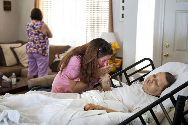 Linda Rolain is soothed by friend Toni at her hospital bed in their living room just days before she passed away following brain surgery in May on Wednesday, June 25, 2014.  She should have had surgery much sooner but due to the problems on the exchange she wasn't able to receive insurance until mid May.
