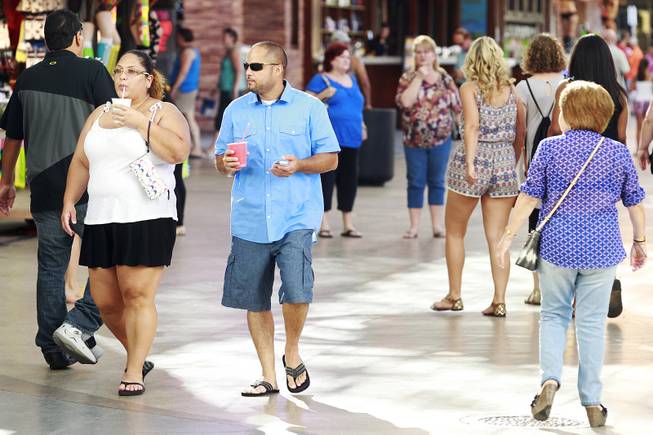 Pedestrians stroll with drinks at the Fremont Street Experience Thursday, July 17, 2014.