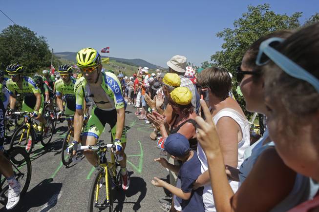Spectators applause as the pack with team Tinkoff Saxo riders climbs during the twelfth stage of the Tour de France cycling race over 185.5 kilometers (115.3 miles) with start in Bourg-en-Bresse and finish in Saint-Etienne, France, Thursday, July 17, 2014. 