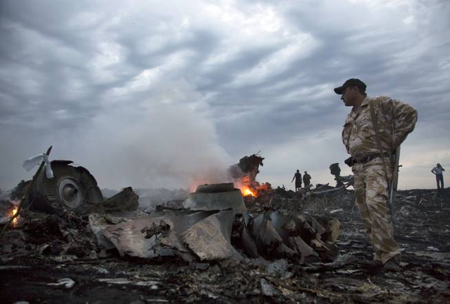 People walk amongst the debris, at the crash site of a passenger plane near the village of Grabovo, Ukraine, Thursday, July 17, 2014.  A Ukrainian official said a passenger plane carrying 295 people was shot down Thursday as it flew over the country and plumes of black smoke rose up near a rebel-held village in eastern Ukraine. Malaysia Airlines tweeted that it lost contact with one of its flights as it was traveling from Amsterdam to Kuala Lumpur over Ukrainian airspace.  