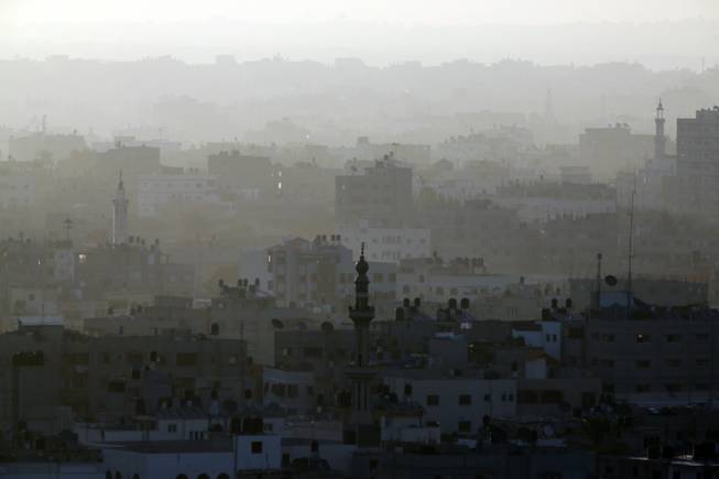 A hazy Gaza City is seen in the northern Gaza Strip early Friday, July 18, 2014. The heavy thud of tank shells, often just seconds apart, echoed across the Gaza Strip early Friday as thousands of Israeli soldiers launched a ground invasion, escalating a 10-day campaign of heavy air bombardments to try to destroy Hamas' rocket-firing abilities and the tunnels militants use to infiltrate Israel.