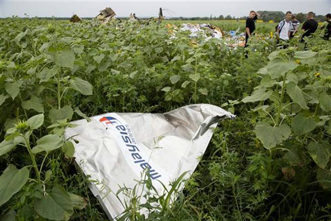 A piece of plane wreckage with Malaysia Airlines' logo lies in the grass as a group of Ukrainian coal miners searches the crash site near the village of Rozsypne, Ukraine, Friday, July 18, 2014. The Malaysian plane ended up in burning pieces Thursday, killing all 298 aboard.