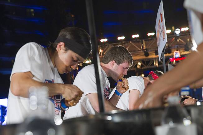 Adrian "The Rabbit" Morgan, center, competes in the 2014 Hooters "World-Wide Wing Eating Championship" at the Hard Rock pool Tuesday, July 22, 2014.