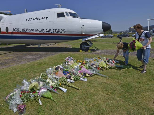 People lay flowers in front of a plane prior a ceremony to mark the return of the first bodies, of passengers and crew killed in the downing of Malaysia Airlines Flight 17, from Ukraine at Eindhoven military air base, Wednesday, July 23, 2014. After being removed from the planes, the bodies are to be taken in a convoy of hearses to a military barracks in the central city of Hilversum, where forensic experts will begin the painstaking task of identifying the bodies and returning them to their loved ones. 
