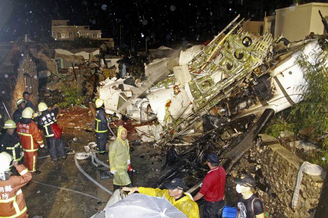 Rescue workers work next to the wreckage of TransAsia Airways flight GE222 which crashed while attempting to land in stormy weather on the Taiwanese island of Penghu, late Wednesday, July 23, 2014.