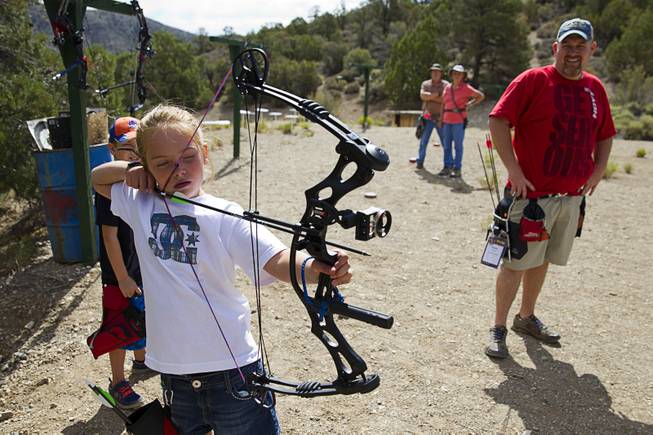 Justice Lavin, 8, takes aim at a target as Jeremy Beard looks on at the Las Vegas Archers Spring Mountain Range near Mountain Springs Sunday, July 20, 2014.