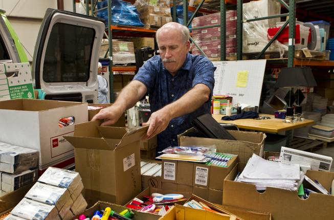 Tim McCubbin, director of the Public Education Foundation's Teacher EXCHANGE, grabs a box off the Cargo Glide installed on their Teacher Exchange Express van within the warehouse on Tuesday, July 22, 2014.