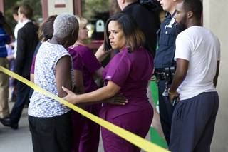 A hospital worker views police activity near the scene of a shooting at a wellness center attached to Mercy Fitzgerald Hospital in Darby, Pa., on Thursday, July 24, 2014. A doctor grazed by gunfire from a patient who had entered his office in a suburban hospital's psychiatric unit stopped him by returning fire with his own gun and injuring him, authorities said.