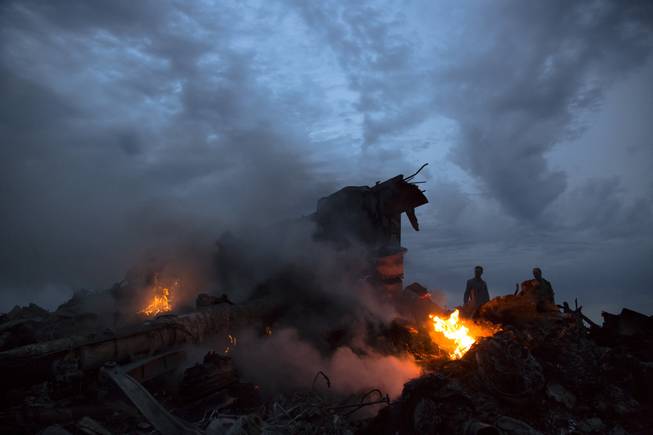 This July 17, 2014, file photo show people walking amongst the debris at the crash site of Malaysia Airlines Flight 17 near the village of Hrabove, eastern Ukraine.