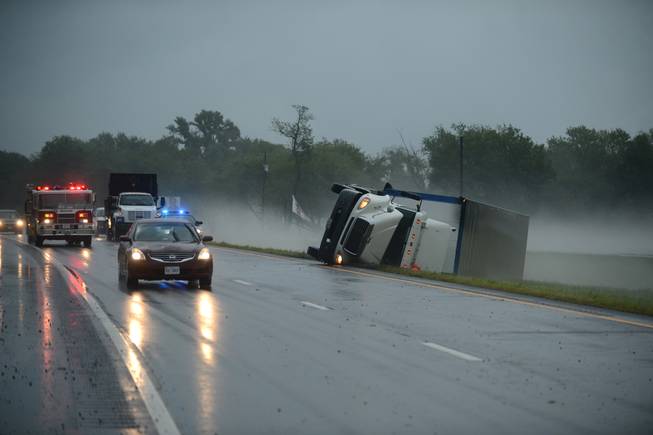 A tractor trailer truck lies on its side in the median of U.S. Route 13 in Cheriton, Va., while a fire engine responds to a nearby campground after a severe storm passed through the area, Thursday, July 24, 2014.