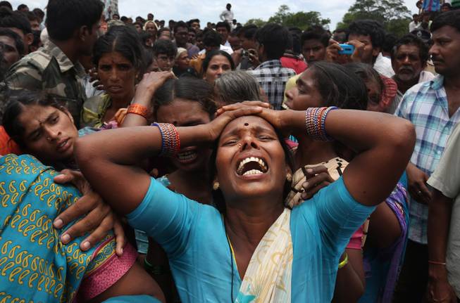 AP10ThingsToSee - A relative of a victim cries at the site of a train that crashed into a school bus in Medak district in the southern Indian state of Telengana, Thursday, July 24, 2014. Twelve children were killed in the crash at an unmanned railroad crossing in southern India, police said. 