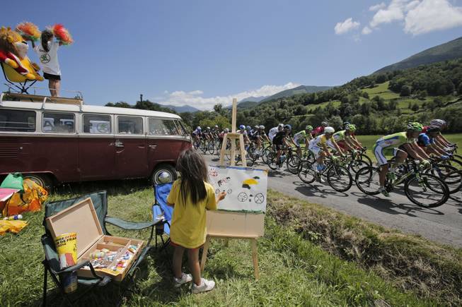 AP10ThingsToSee - A child makes a painting of cyclists as the pack with Australia's Simon Gerrans passes during the sixteenth stage of the Tour de France cycling race over 237.5 kilometers (147.6 miles) with start in Carcassonne and finish in Bagneres-de-Luchon, France, Tuesday, July 22, 2014. 
