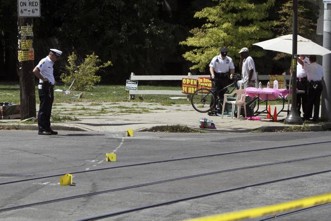Investigators gather at the scene of a fatal accident in North Philadelphia, Friday July 25, 2014. Two children were killed and three people critically injured when a hijacked car lost control and hit a group of people near a fruit stand, according to police. (AP Photo/ Joseph Kaczmarek)