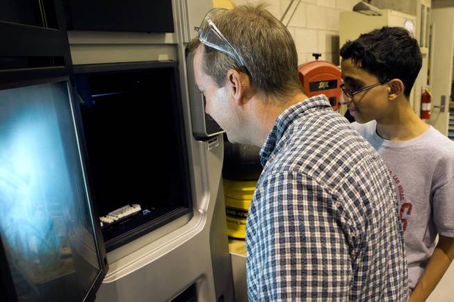 UNLV Professor Brendan O'Toole, left, and Kahrem Trabia, a high school senior at A-Tech and summer program participant, check the progress made on parts of the prototype Robohand being printed on a 3D printer June 19, 2014 at the University of Nevada, Las Vegas. 