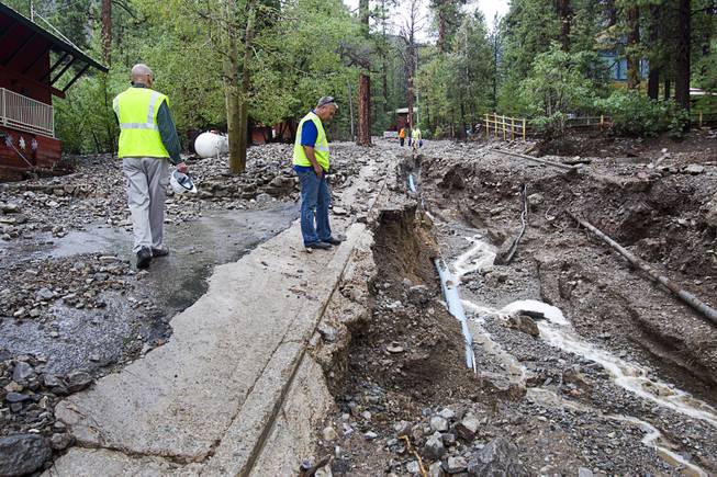 Las Vegas Water District employee Tom Georgi, center, looks over damage to Rainbow Canyon Boulevard in the Rainbow Subdivision on Mt. Charleston Monday, July 28, 2014. The neighborhood was hit hard by flooding and debris in runoff last year as well.