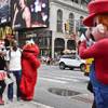 A visitor to Times Square stands for photos with costumed characters Monday, July 28, 2014, in New York. New York Mayor Bill de Blasio said Monday that he believes the people wearing character costumes in Times Square should be licensed and regulated.