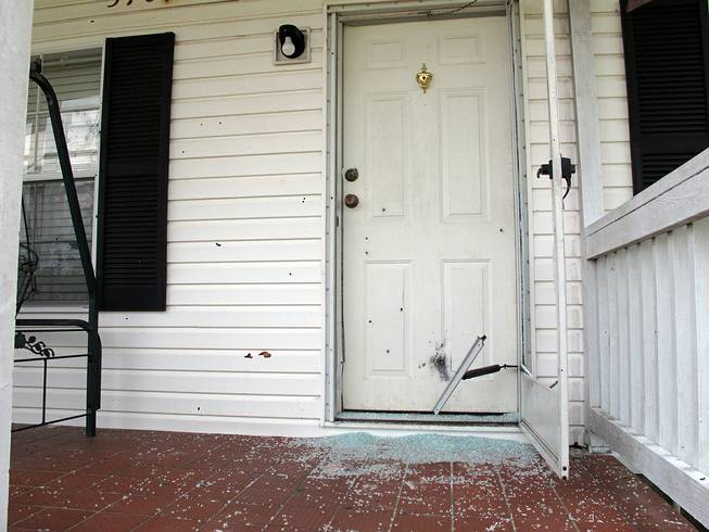 The front door of a home is riddled with bullet holes in Fayetteville, N.C., on Wednesday, July 30, 2014. An angry husband sprayed his father-in-law's house with bullets from two 30-round magazines, killing two people.
