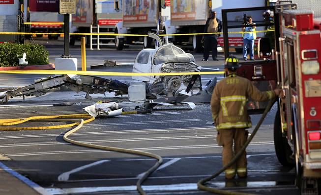 The wreckage of a small plane sits in the parking lot of shopping center Wednesday afternoon, July 30, 2014, in San Diego. Police said that one woman was killed and one hurt in the crash. 