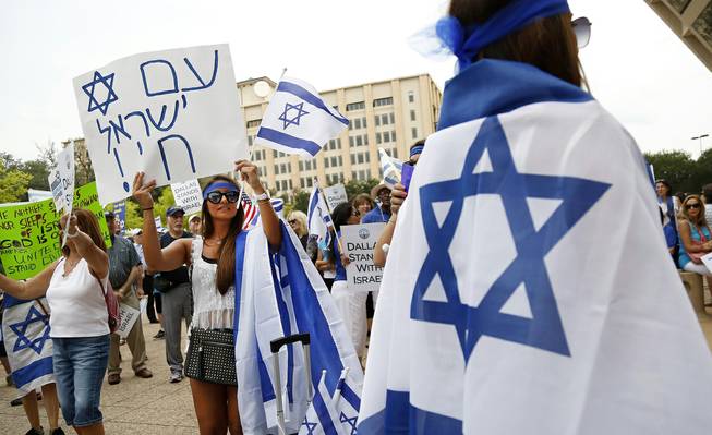 Rebecca Abramov, second from left, holds up a sign in Hebrew during a rally in support of Israel in front of city hall in Dallas, Texas, Wednesday, July 30, 2014. 
