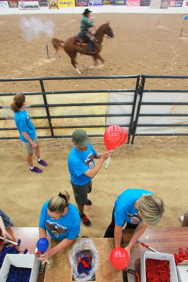 Volunteers fill target balloons as a cowboy competes during the Cowboy Mounted Shooting Association's Western U.S. ChampionshipThursday, July 31, 2014 at the South Point.
