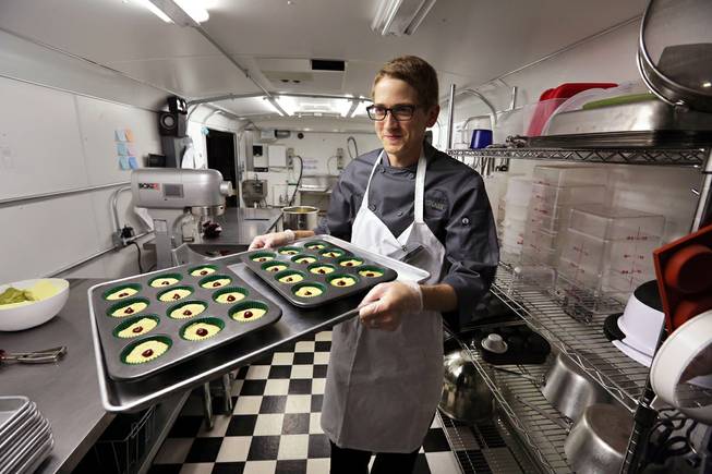In this June 19, 2014, file photo, chef Alex Tretter carries a tray of cannabis-infused peanut butter and jelly cups to the oven for baking at Sweet Grass Kitchen, a well-established Denver-based gourmet marijuana edibles bakery which sells its confections to retail outlets throughout the state. 
