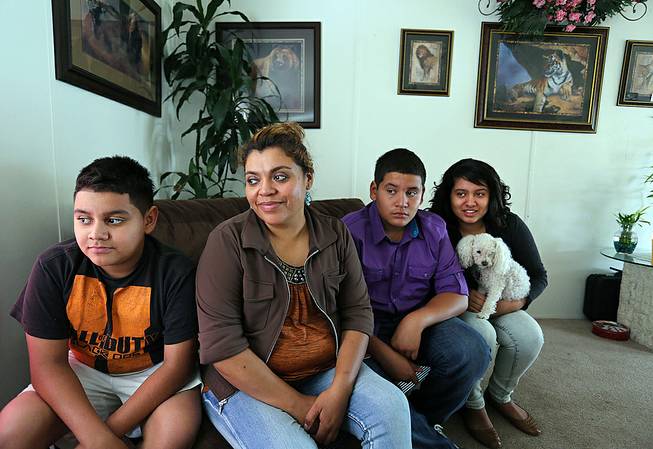 Adriana Gaytan, who came to Colorado in 1997 from the Mexican state of Zacatecas, second from left, sits at home with her children who were born in the U.S. from left to right, Osbaldo, 11, Oscar 13, Indhira, 14, and their dog Kissy, in Aurora, Colo., Thursday, July 31, 2014. Gaytan will get a driver's license soon, as Colorado will begin issuing driver's licenses and identification cards to people who are in the country illegally or have temporary legal status. 