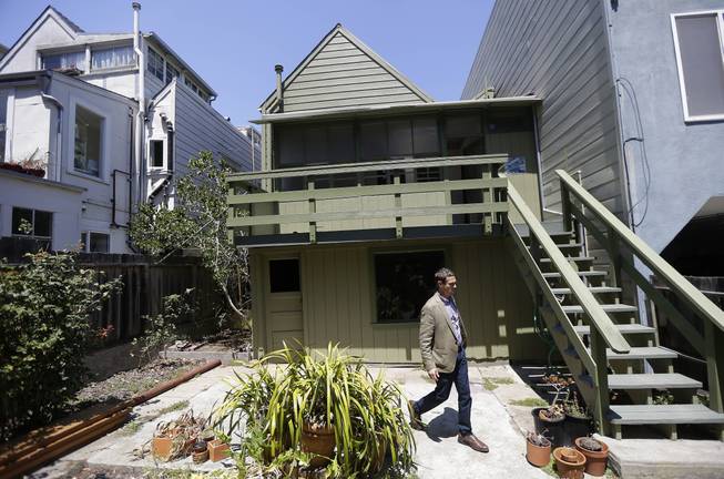 George Limperis, a realtor with Paragon Real Estate Group, walks in the backyard of a property in the Noe Valley neighborhood in San Francisco, Wednesday, July 30, 2014. In the souped-up world of San Francisco real estate, where the median selling price for homes and condominiums hit seven figures for the first time last month, the cool million that would fetch a mansion on a few acres elsewhere will now barely cover the cost of an 800-square foot starter home that needs work and may or may not include private parking.