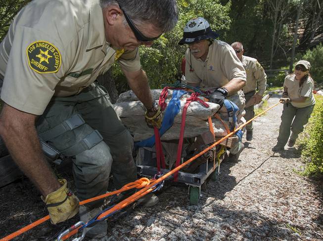 Members of the Los Angeles Sheriff’s Department Search and Rescue team, Mike Leum, left, John McKently, center, and Janet Henderson, right, help to roll a 16-17-million-year-old fossil lodged in a rock weighing about 2,000 pounds up a steep hillside on a customized cart in Rancho Palos Verdes, Calif. on Friday, Aug. 1, 2014. 
