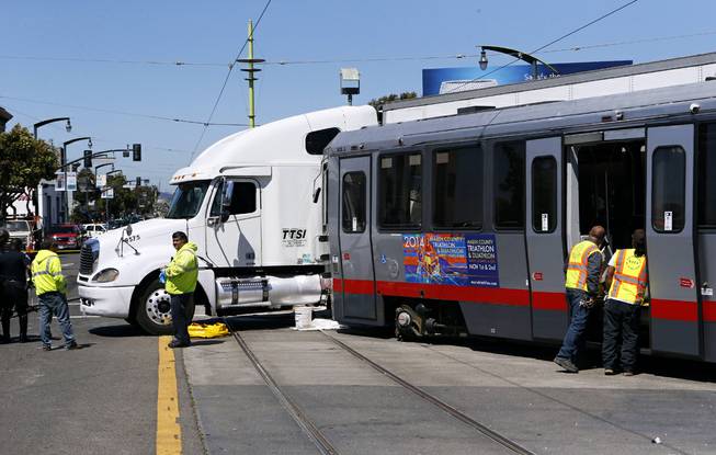 Emergency personnel arrive at the scene of a collision between a big rig truck and a MUNI light rail vehicle at the intersection of Innes and 3rd streets on Friday, Aug. 1, 2014, in San Francisco, Calif.