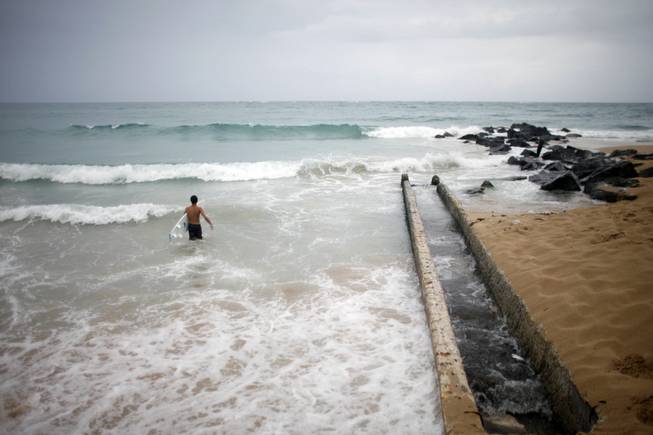 A surfer enters the water to take advantage of the high waves in San Juan, Puerto Rico, on Saturday, Aug. 2, 2014. Bertha pushed just south of Puerto Rico on Saturday as it unleashed heavy rains and strong winds across the region.