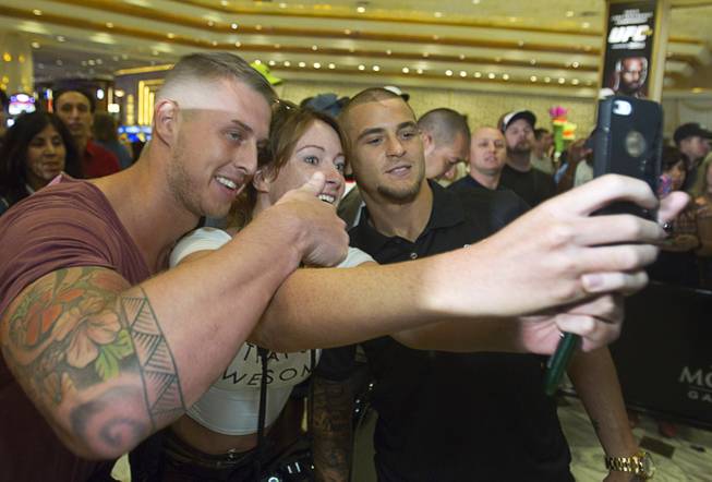 UFC featherweight fighter Dustin Poirier, right, poses with fans Lewis and Joanne Standring of Manchester, England during a UFC press conference at the MGM Grand Monday Aug. 4, 2014.