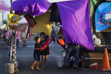Kids make their way through an art vendor’s space with colorful cloth at First Friday activities on Friday, August 1, 2014.
