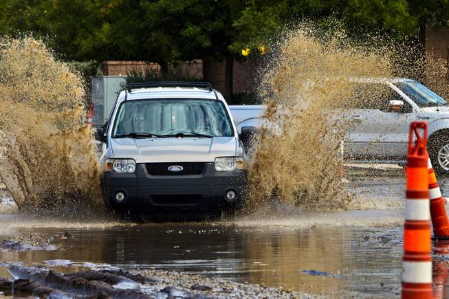 A car is driven quickly through deep water collecting due to recent heavy rains along West Grand Teton Drive at the intersection of North Tenaya Way on Monday, August 4, 2014.