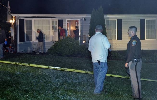 In this Monday, Aug. 4, 2014, photo released by the Culpeper County Sheriff's Office, police investigate the home where a family of five, including three children, were found shot to death Sunday night, in Culpeper, Va.