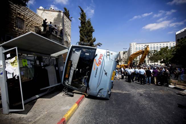 A damaged bus flipped over after attack in Jerusalem, Monday, Aug. 4, 2014. An Israeli-declared cease-fire and troop withdrawals slowed violence in the Gaza war Monday, though an attack on Israeli bus that killed one person in Jerusalem underscored the tensions still simmering in the region.
